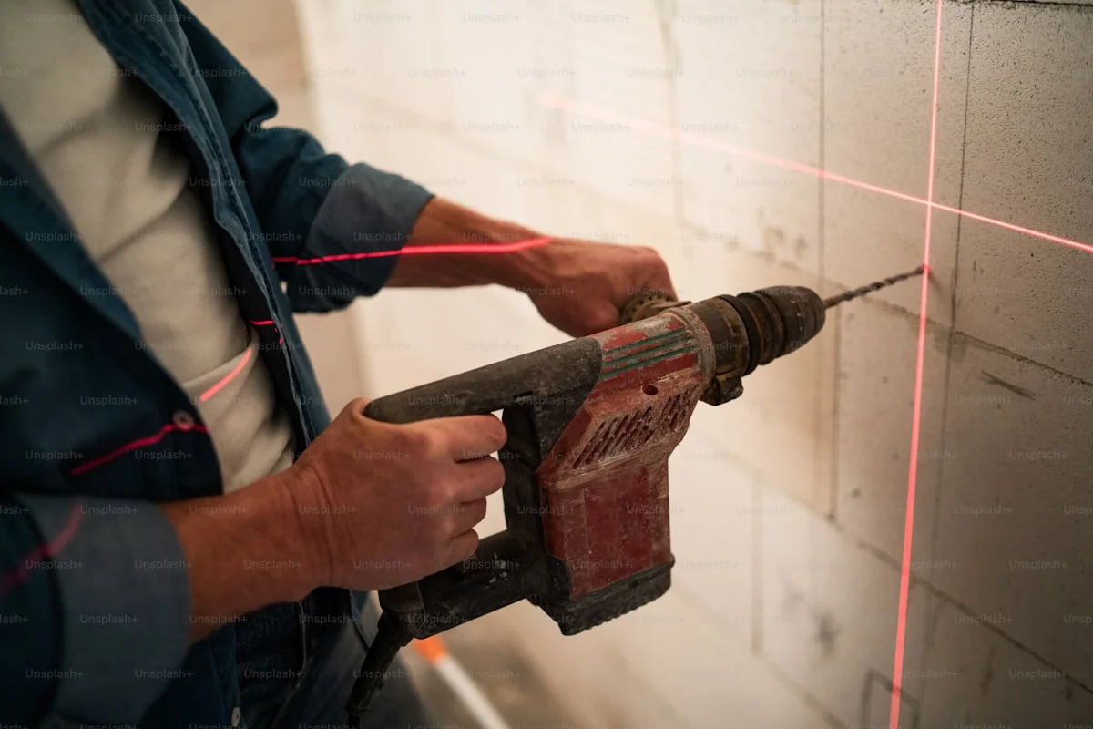 Artisan utilisant une perceuse sur un mur